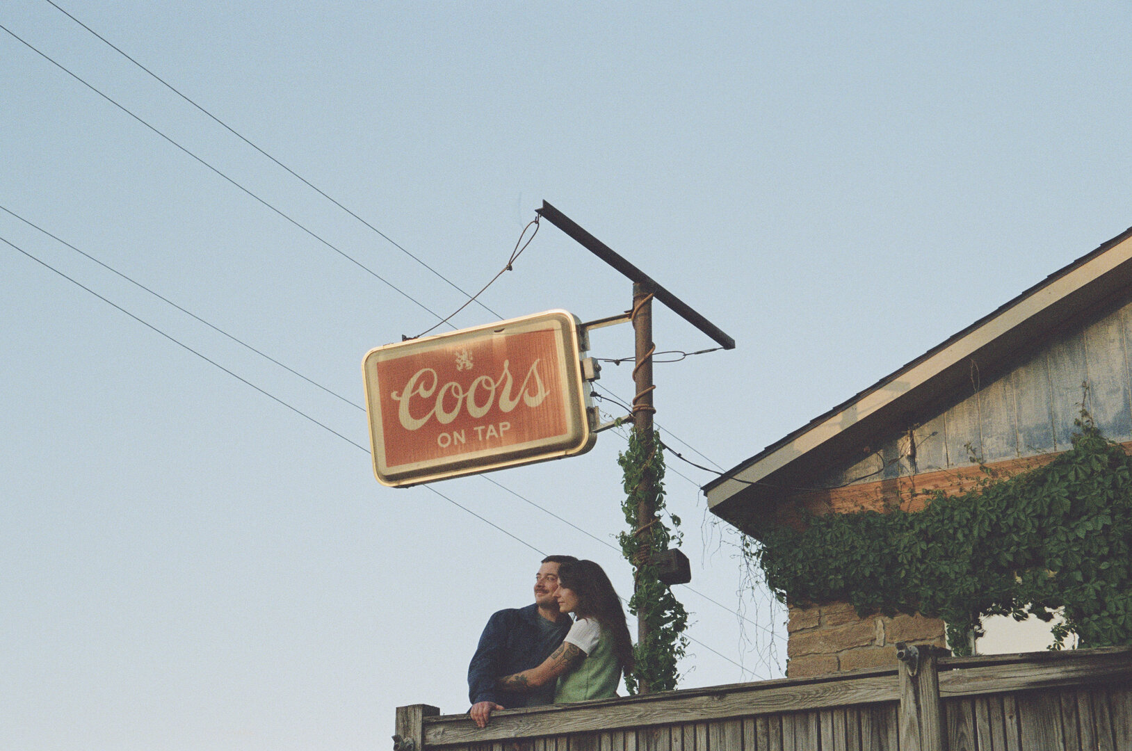 Andy and Brit sitting together by a vintage Coors sign